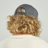 A grey cap with a strap at the back, worn by a person with curly, shoulder-length blonde hair.