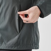 A woman's hand adjusting a zipper on a grey wind jacket, featuring a side pocket and a smooth fabric texture.