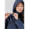 A woman adjusts the fastening on a navy lightweight rain jacket with a hood, featuring a logo on the sleeve.