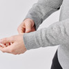 A grey 1/4 zip pullover with long sleeves, featuring wrist cuffs, held by a person.