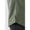 A close-up of a green button-up shirt, featuring a curved hem and a small branding label.