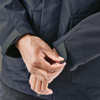 A close-up of a person adjusting the cuff of a dark navy jacket featuring a logo.