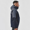 A navy blue men's rain jacket with a hood, featuring a zippered front and side pockets, alongside a model.