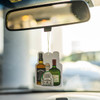 A custom air freshener featuring illustrations of liquor bottles, hanging from a car's rearview mirror.