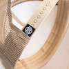 A beige cap featuring a mesh back and a logo on the side, highlighting its headwear design.