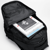 A black backpack with a partially open zipper, revealing magazines and documents inside. It features a logo on the exterior.