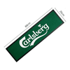 A green rubber bar mat featuring a logo, measuring 89 cm by 25 cm, with black trim.
