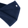 A navy cotton golf towel with a textured surface and a small branding label in one corner.
