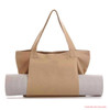 A tan canvas bag with a yoga mat rolled up and secured inside. The bag has two handles and a logo.
