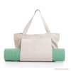 A canvas bag in light grey with two handles, holding a green yoga mat. The bag features a logo on it.