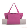 A pink canvas bag with two handles, holding a rolled-up yoga mat. The bag features a logo.