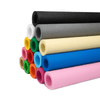 A stack of vibrant rolls of non-woven fabric in various colours, including blue, pink, green, and black, with a logo visible.