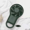 A portable pocket fan in dark green with a handle, featuring a circular fan design.