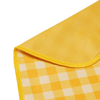 A yellow picnic blanket with a checkered pattern and a smooth edge. It features a branding logo in one corner.