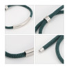 A metal woven bracelet featuring a dark green woven design and sleek silver accents.