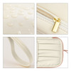 A cream PU toiletry bag with a water-resistant surface, gold zipper, sturdy handle, and organised interior compartments.
