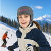 A thickened grey earflap hat with a logo, worn by a smiling woman in snow-covered mountains.
