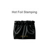 A black zipperless portable makeup bag with a gathered top and gold branding, featuring a smooth satin finish.