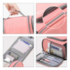 A pink travel storage bag with a handle, featuring mesh pockets and compartments for organisation.