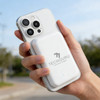 A white 5000mAh magnetic wireless power bank is attached to a smartphone, held in a hand outdoors. It has a logo.