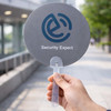 A round grey hand fan with a clear handle, featuring a logo and the words "Security Expert".