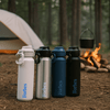A drink bottle collection featuring white, silver, navy, and black bottles, each with a logo, set in a camping environment.
