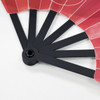 A plastic hand fan with red and white design, featuring black spokes and a circular base.