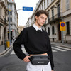 A black fanny pack worn around the waist, with a logo, against an urban street backdrop.