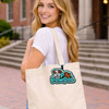 A woman carries a cream-coloured tote bag featuring a colourful logo with a dog design.