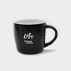 A black ceramic mug with a curved design and a handle, featuring a logo on the front.