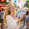 A woman holds seven vibrant, patterned plastic hand fans at an outdoor event with colourful lights in the background.