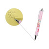 A pink ballpoint pen with a decorative design and silver tip, showcasing 1.0mm black ink writing on yellow paper.