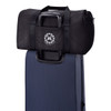 A black duffel bag positioned on top of a blue suitcase, featuring a logo on the front.