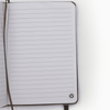 An open notebook with lined pages and a logo in the bottom corner. The cover is a neutral colour.