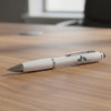 A white stylus pen with a silver clip resting on a wooden table, featuring a logo on its body.