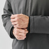 A close-up of a person's hands adjusting the cuffs of a dark grey thermal jacket with a logo.