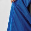 A close-up of the interior lining of a blue rain jacket, showing a textured fabric and a hands holding the jacket.