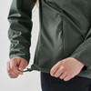 A green women's full zip rain jacket with a drawstring at the hem being adjusted by a person.