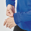 A close-up of a person's hands adjusting the sleeve of a blue long-sleeve T-shirt. The shirt has a logo.