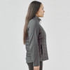 A women's softshell jacket in grey, featuring a quilted design and a zip closure. The jacket includes a logo.