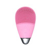 A pink silicone facial cleansing brush with textured surface and control buttons, featuring a metallic base.