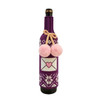 A drink bottle inside a purple custom knitted sleeve, featuring pink pom-poms and a heart design.