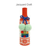A drink bottle is wrapped in a knitted sleeve featuring orange and white patterns, with blue pom-poms and a logo.