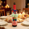 A drink bottle is enveloped in a red and white knitted sleeve with green pom-poms, sitting on a festive table.
