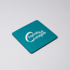 A square coaster in teal featuring a logo, with a black edge.