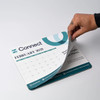 A mouse mat in light blue and white, featuring a calendar for February 2025 and a logo.