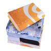 A stack of five colourful face washers in shades of orange, blue, and various patterns, featuring a logo.