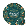 A round beach towel featuring a tropical design with green leaves, toucans, and flowers, folded beside it.