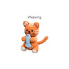 An orange crocheted cat holding a blue fish, featuring distinct stripes and a tail, against a light background.
