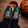 Colourful custom shoe laces in a pair of black and green sneakers, with a basketball and wooden box in the background.